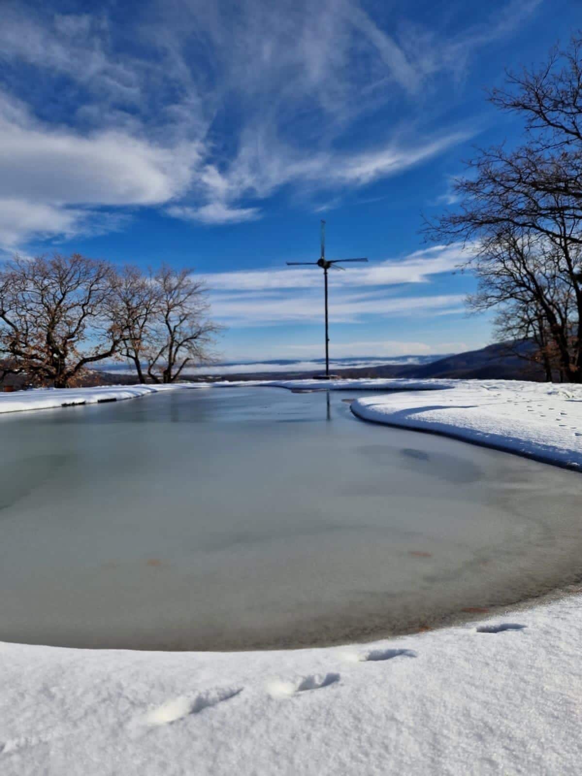 Um lago congelado com uma turbina eólica ao fundo.