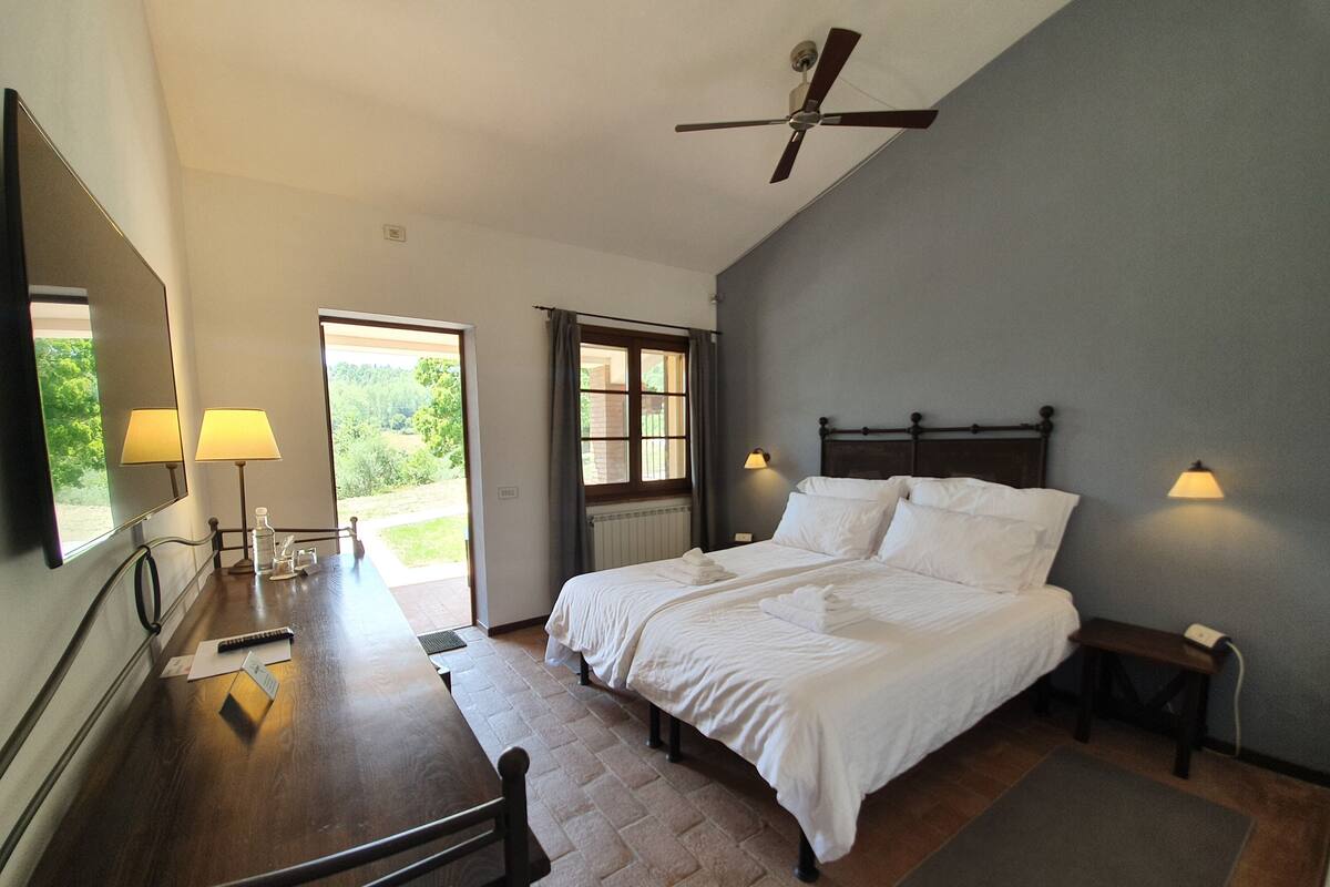 A bedroom with a bed, bedside tables, a desk, and a ceiling fan.