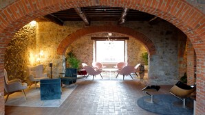 An interior with a brick archway, stone walls, and modern seating.