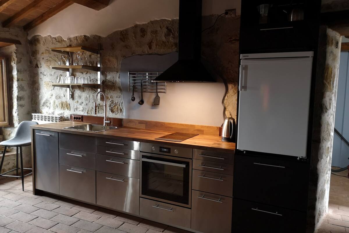 A modern kitchen with a stone wall, stainless steel appliances, and wooden countertops.