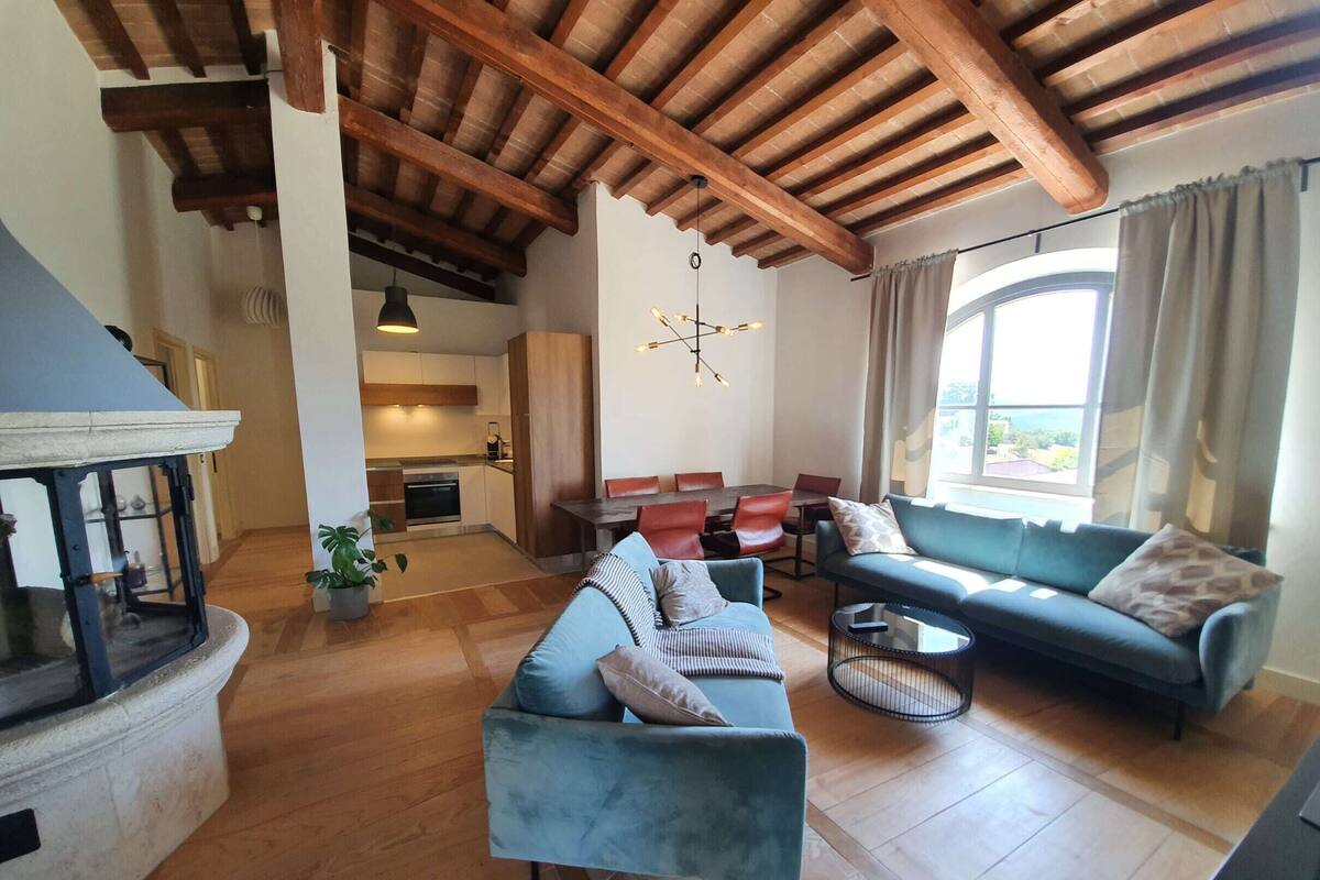 A spacious living area with a wooden ceiling, a dining table, a sofa, and a fireplace.