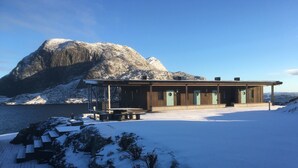 Une cabane avec une façade en bois, une véranda couverte et une vue sur la montagne.