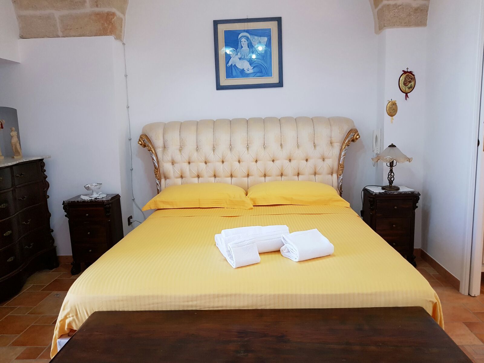 A bedroom with a large bed, two nightstands, a dresser, and a framed picture on the wall.