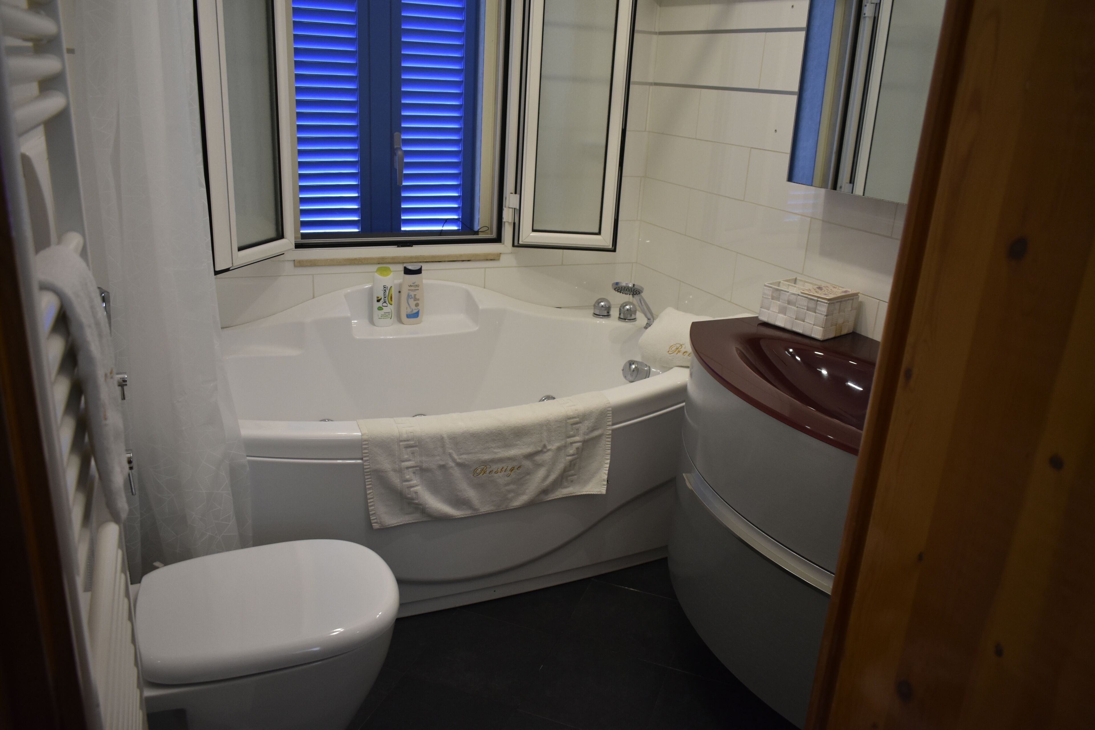 Un baño con una bañera blanca, un inodoro blanco y un tocador de madera con espejo.