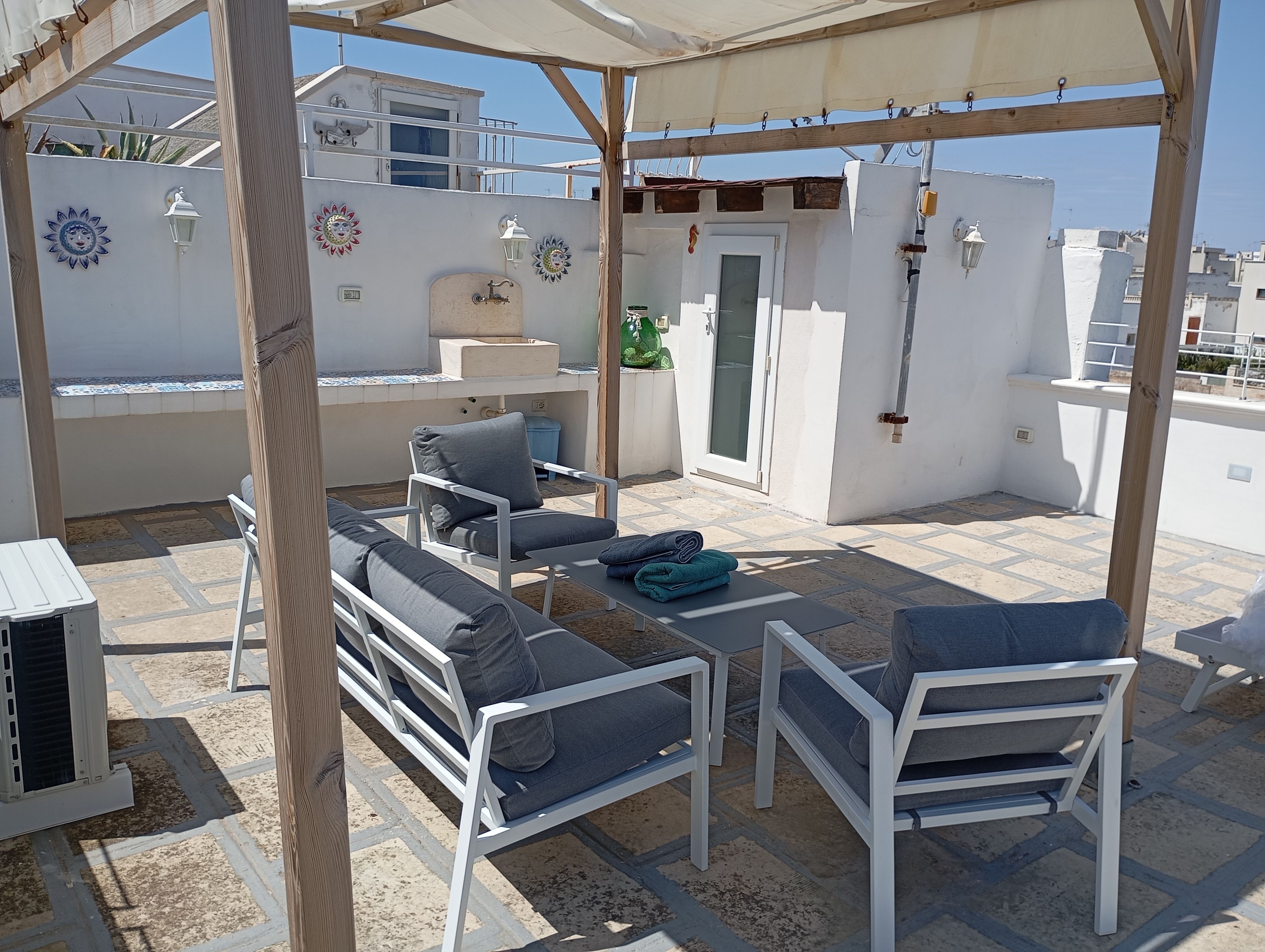 An outdoor patio area with white furniture, a water feature, and decorative wall art.