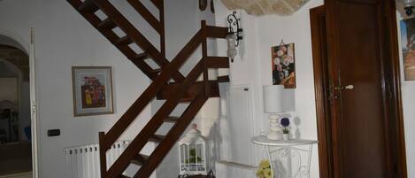 A staircase with wooden railings, a white radiator, a small table with a vase, and a door.