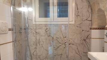 A bathroom with a shower enclosure, a toilet, and a sink.
