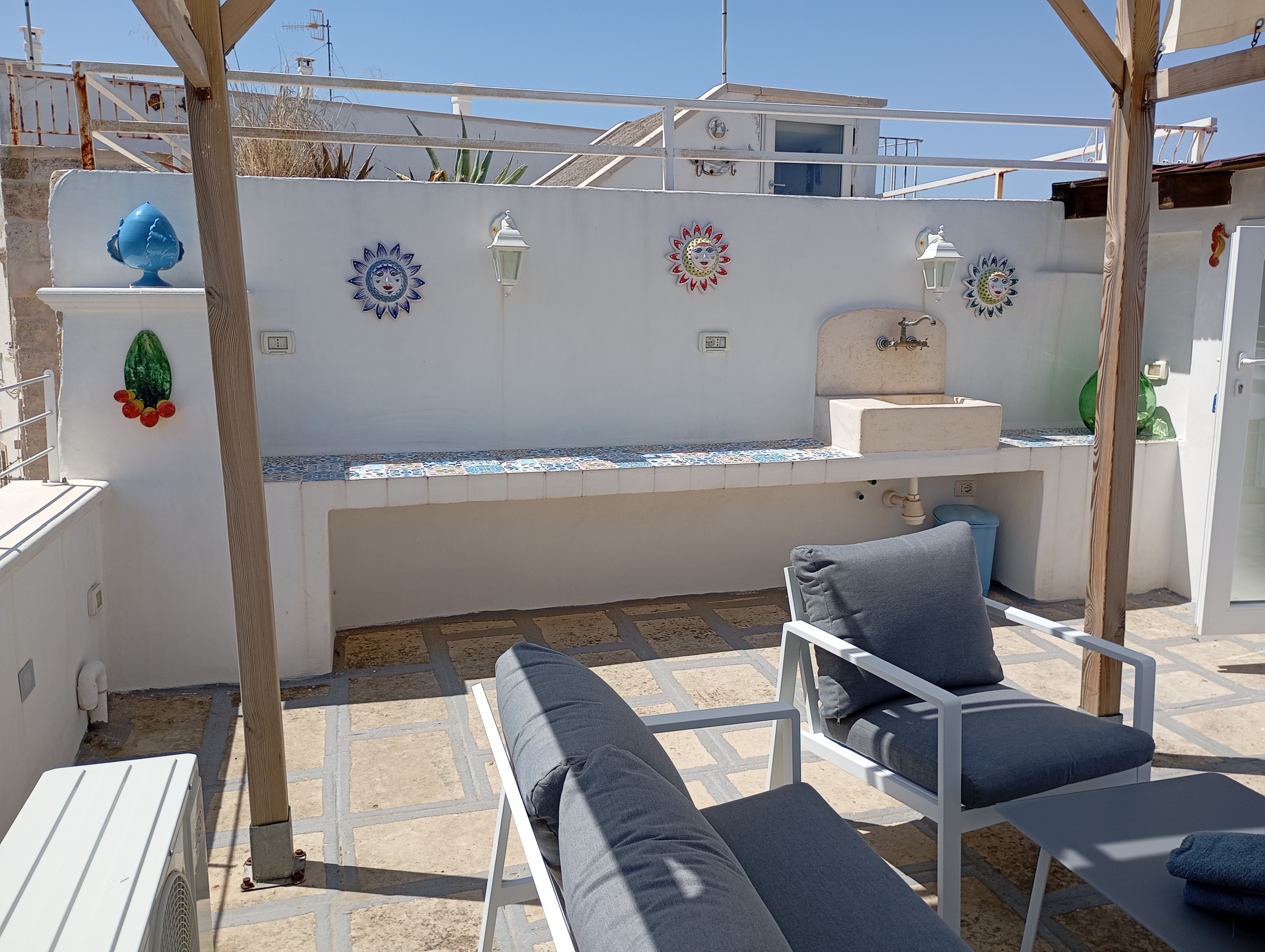 An outdoor seating area with a white table, a blue chair, and a cushioned bench.
