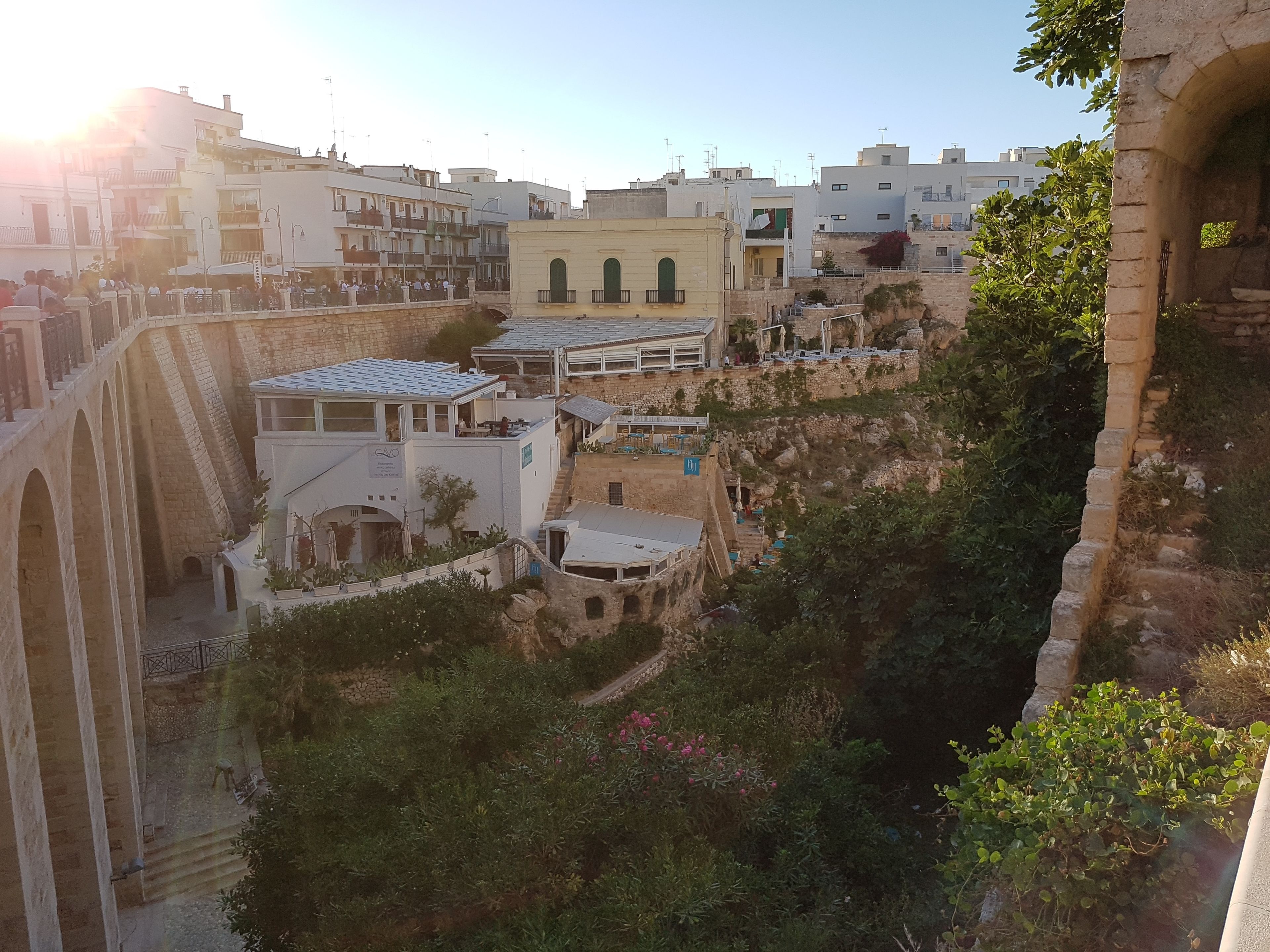 A view of a historic town with stone buildings, a bridge, and a lush green area.