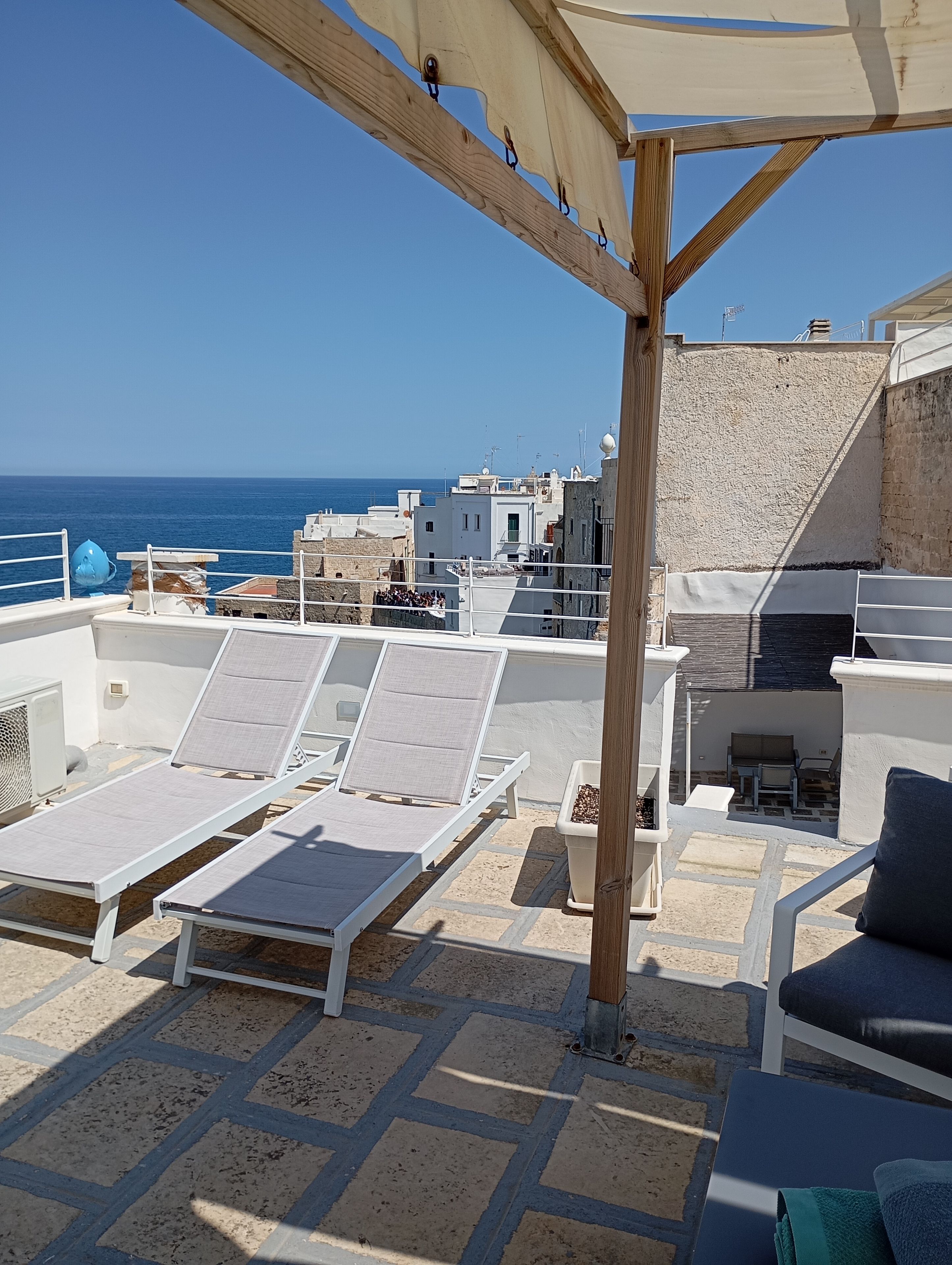 A rooftop terrace with sun loungers and a view of the sea.
