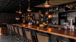 A bar area with a long counter, multiple bar stools, and a variety of bottles and glasses on shelves. - Bode Nashville (Nashville)