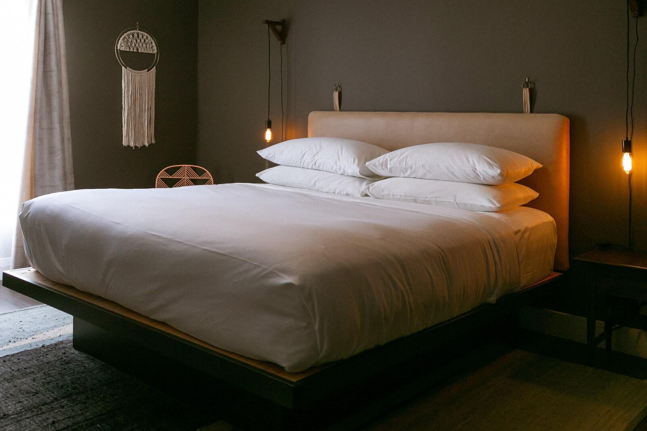 A bed with a wooden frame, white bedding, and two bedside lamps.