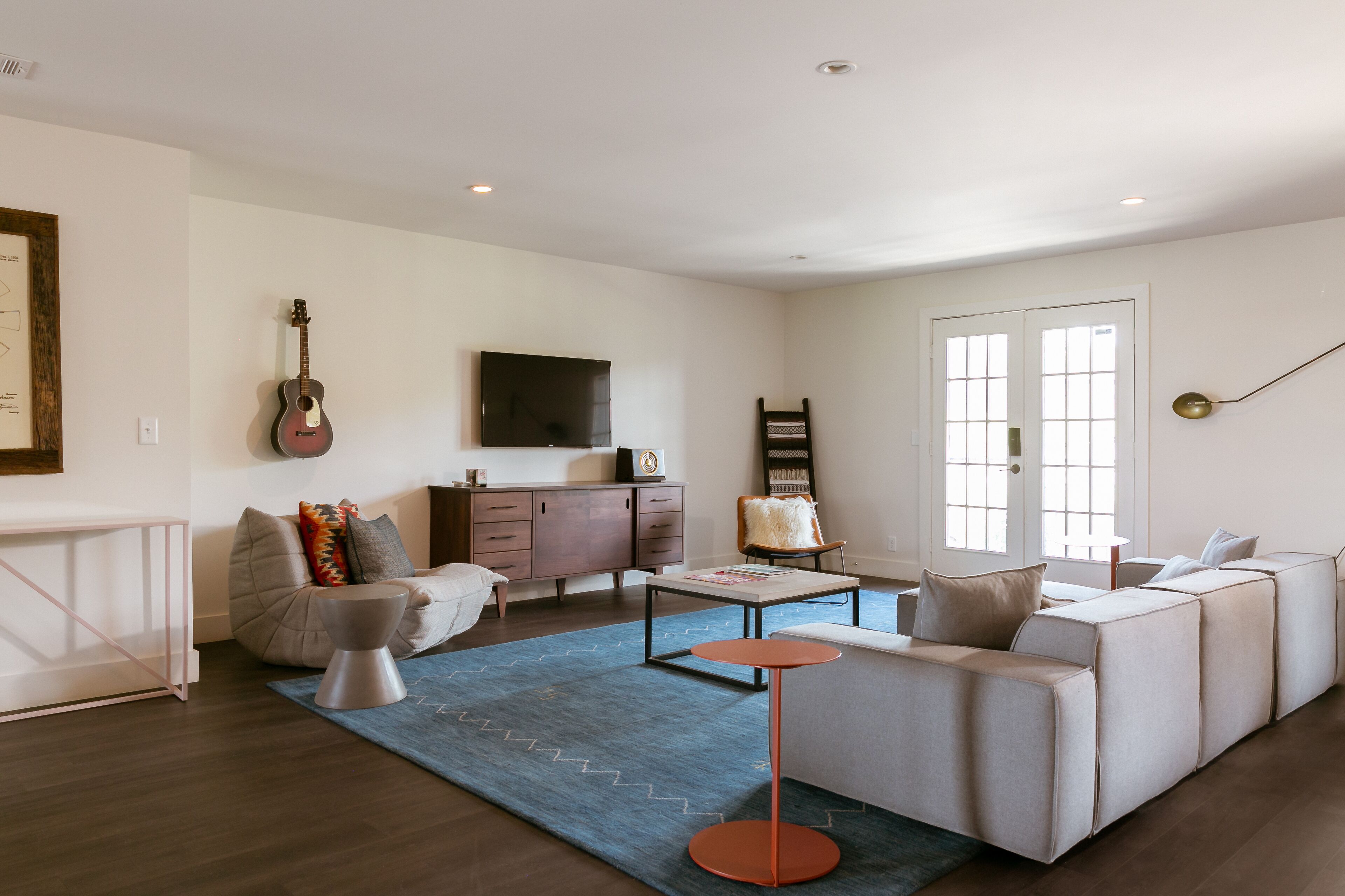 A modern living room with a sofa, coffee table, and a guitar.