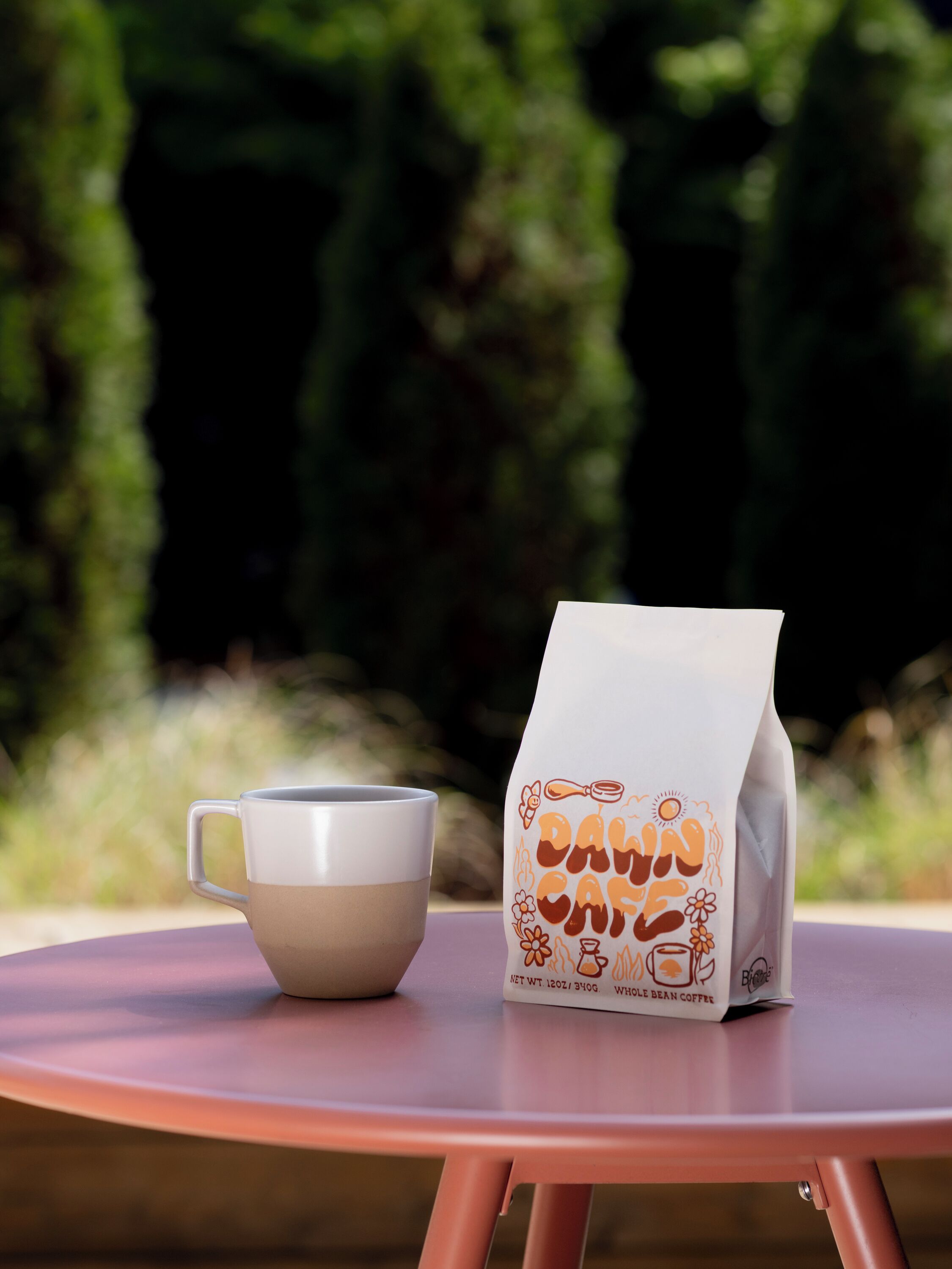 A white paper bag with brown text and a white cup on a round table.