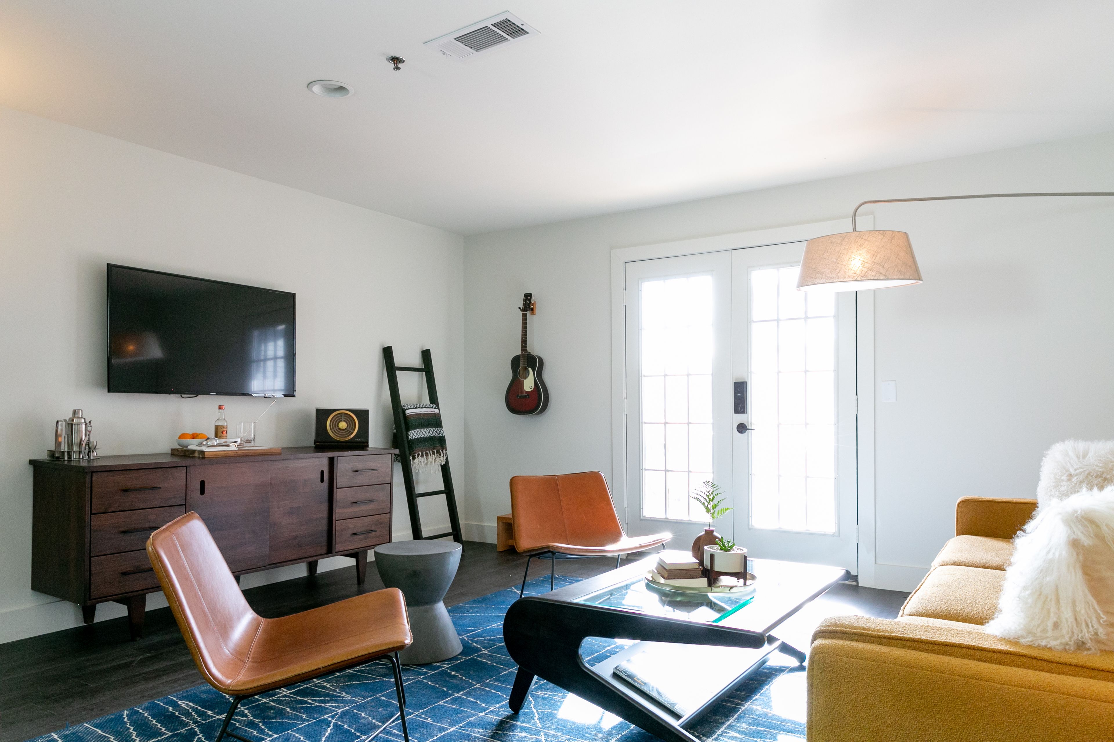 A living room with a flat-screen TV, a guitar, a coffee table, and a sofa.