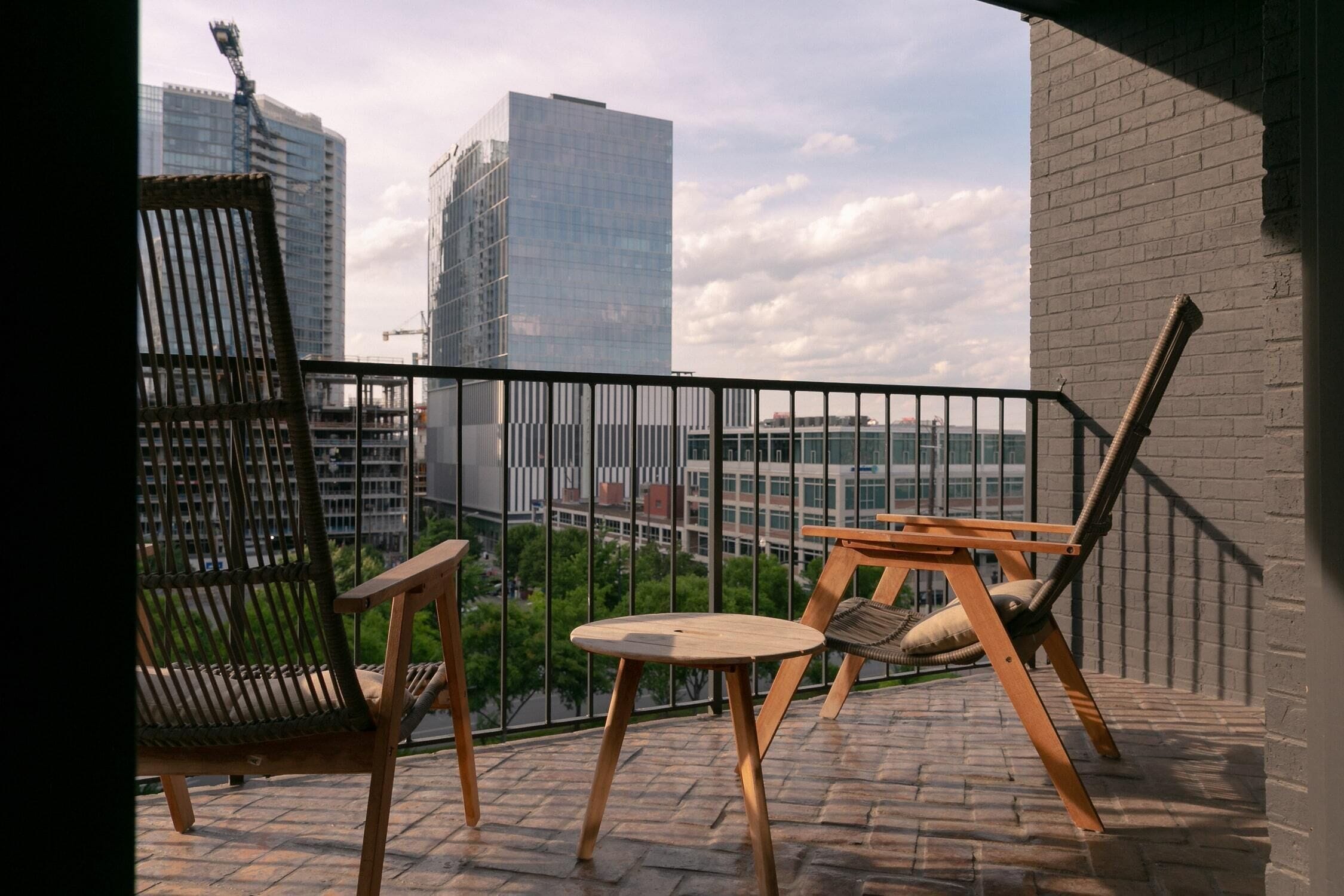 A balcony with a view of a cityscape, featuring a high-rise building, a construction crane, and a clear sky.