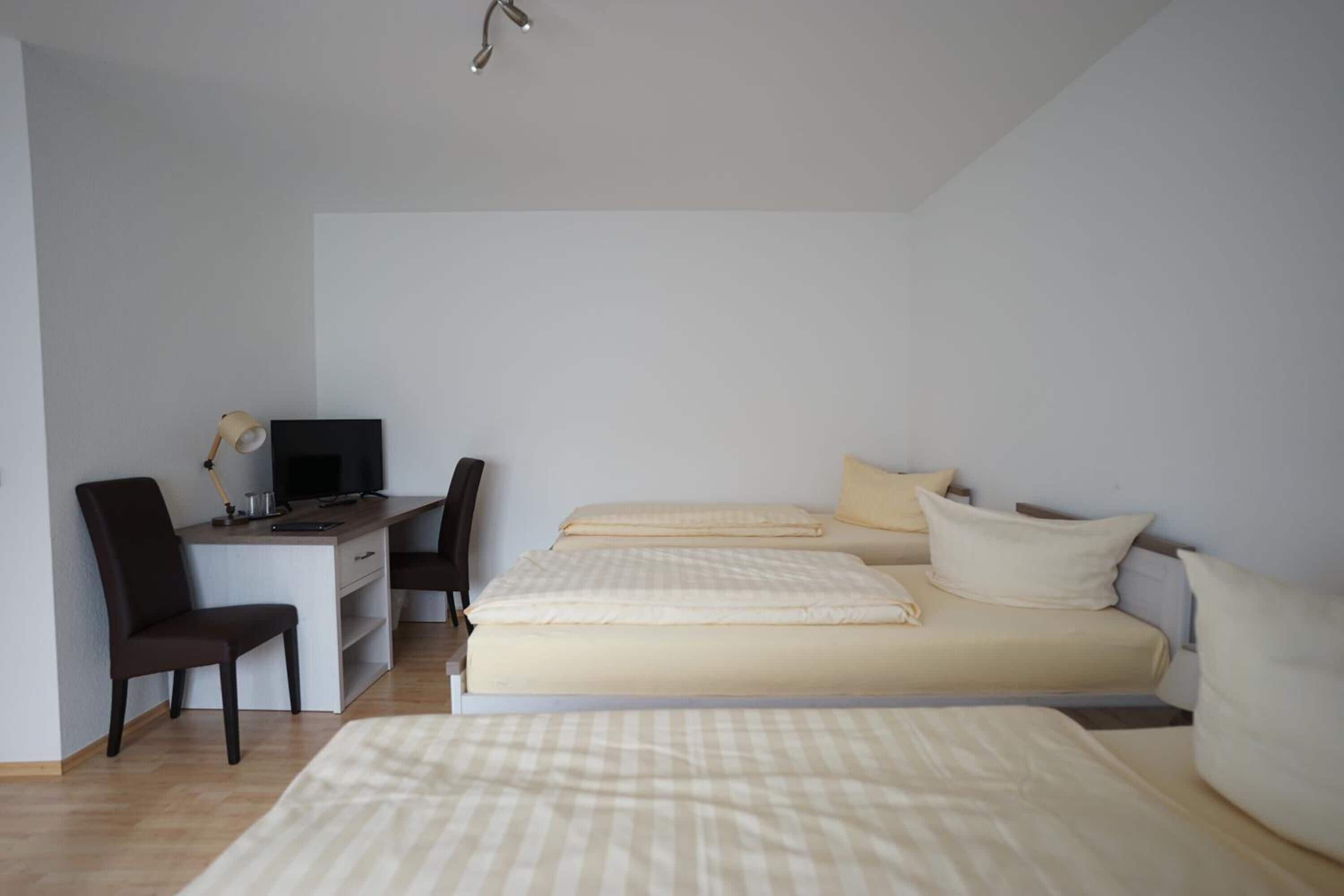 Een slaapkamer met een bed, een bureau met een computer en een stoel.