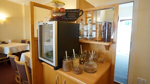 A kitchenette with a refrigerator, a shelf with jars of condiments, and a sign in a foreign language. - Hotel Sauer Garni (Neu-Isenburg)