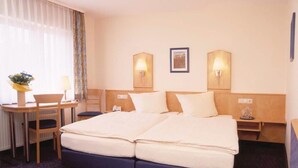 A hotel room with a double bed, two bedside tables, a chair, a desk, and a lamp. - Hotel Sauer Garni (Neu-Isenburg)