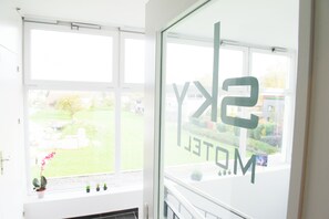 Una habitación con ventanas amplias, vista a un paisaje verde y un cartel con la inscripción 'SKY HOTEL'.