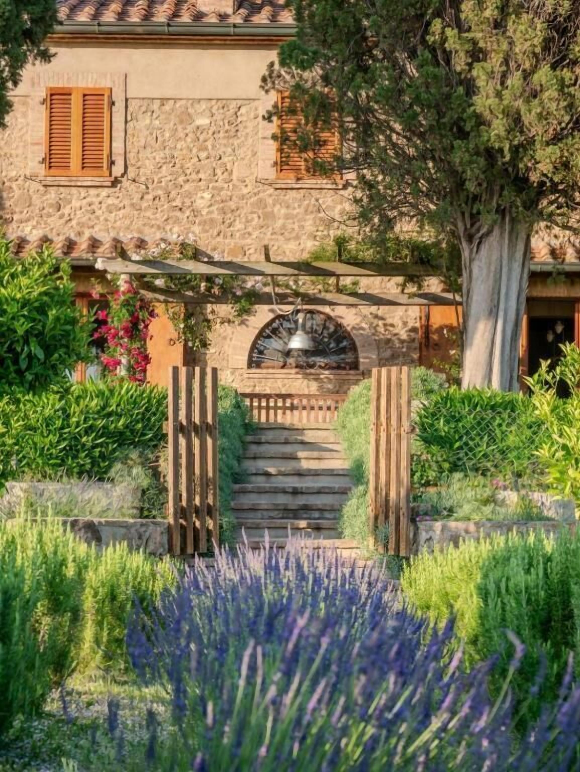 Un edificio in pietra con un cancello di legno, una campana e una scala che conduce a una porta.
