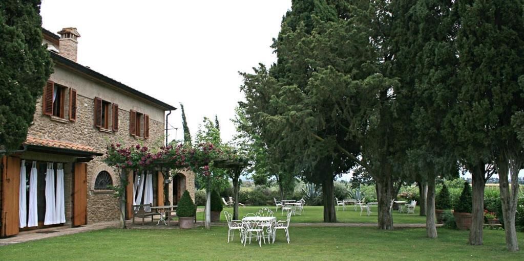 Ein Steingebäude mit Garten, Terrassen-Sitzgelegenheiten und Bäumen.