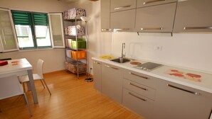 A compact kitchen with a white countertop, a sink, and a dining area with a chair and table. - Egidio studio apartment 2 (Florence)