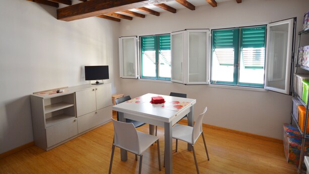 A room with a white table and chairs, a television, and a bookshelf. - Egidio studio apartment 2 (Florence)