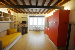 A compact living space with a sofa, a dining table, and a kitchen area with red cabinets. - Egidio studio apartment 1 (Florence)