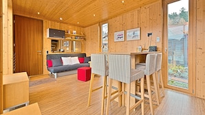 A cozy cabin interior with a wooden ceiling, a sofa, a dining table with chairs, and a large window offering a view of the outdoors. - mein kleinHOTEL Biedenkopf (Biedenkopf)