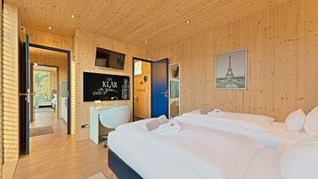 A modern hotel room with wooden paneling, a large bed, a desk, and a television.