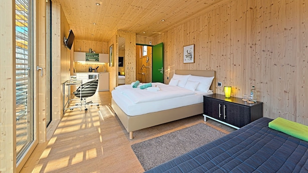 A modern bedroom with a bed, bedside table, and a desk area with a chair. - mein kleinHOTEL Biedenkopf (Biedenkopf)