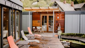 A modern outdoor deck with a wooden pergola, seating area, and a glass door entrance. - mein kleinHOTEL Biedenkopf (Biedenkopf)
