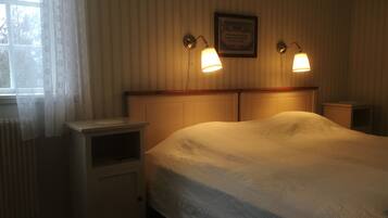 A bedroom with a bed, bedside tables, a window with curtains, and wall-mounted lamps.