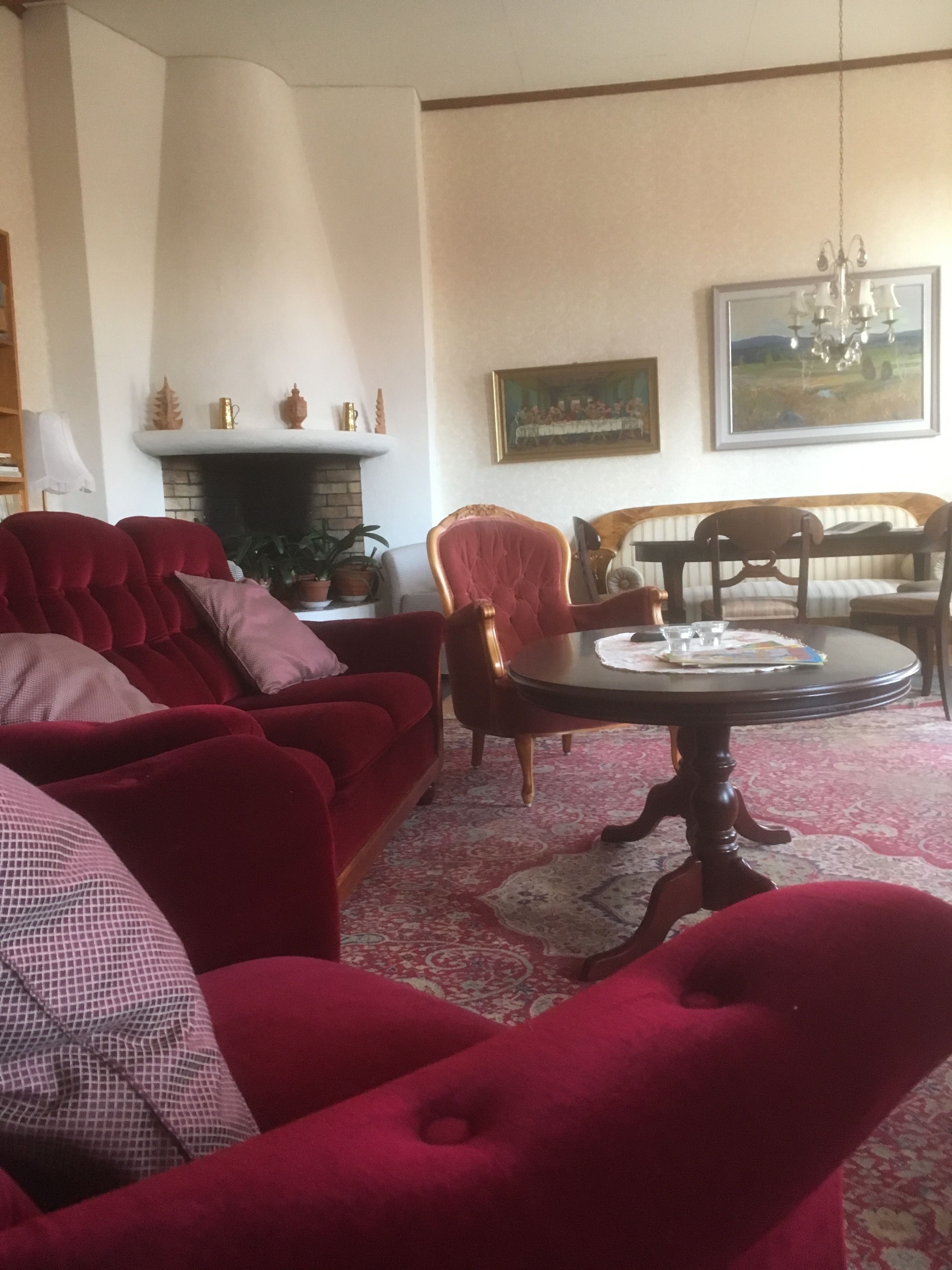 Una sala de estar con un sofá rojo, una mesa de comedor de madera y una chimenea.