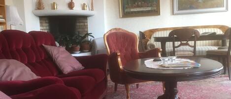 A living room with a red sofa, a wooden dining table, and a fireplace.