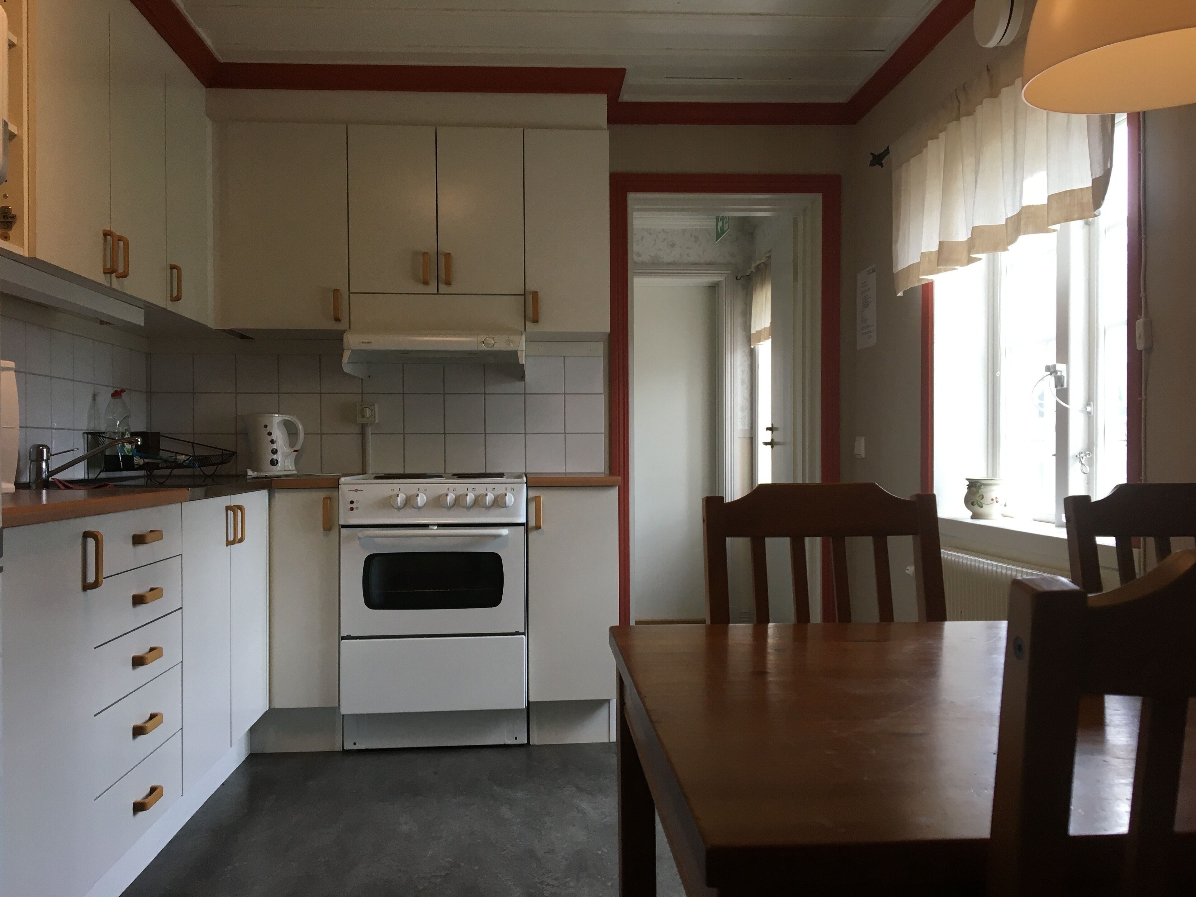 Une cuisine avec des meubles blancs, une cuisinière et une table à manger avec des chaises.