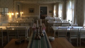 Un espace repas comprenant plusieurs tables et chaises, un ventilateur de plafond et des luminaires fixés au mur.