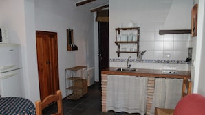 A compact kitchen with a sink, wooden cabinets, and a tiled backsplash. - Casa Rural La Fabrica De Nacelrio (Cazorla)