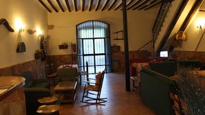 A cozy interior with a stone wall, wooden ceiling beams, a large arched window, and a staircase. - Casa Rural La Fabrica De Nacelrio (Cazorla)