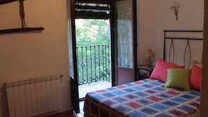 A bedroom with a bed, a radiator, a window with a view of trees, a nightstand, and a lamp. - Casa Rural La Fabrica De Nacelrio (Cazorla)