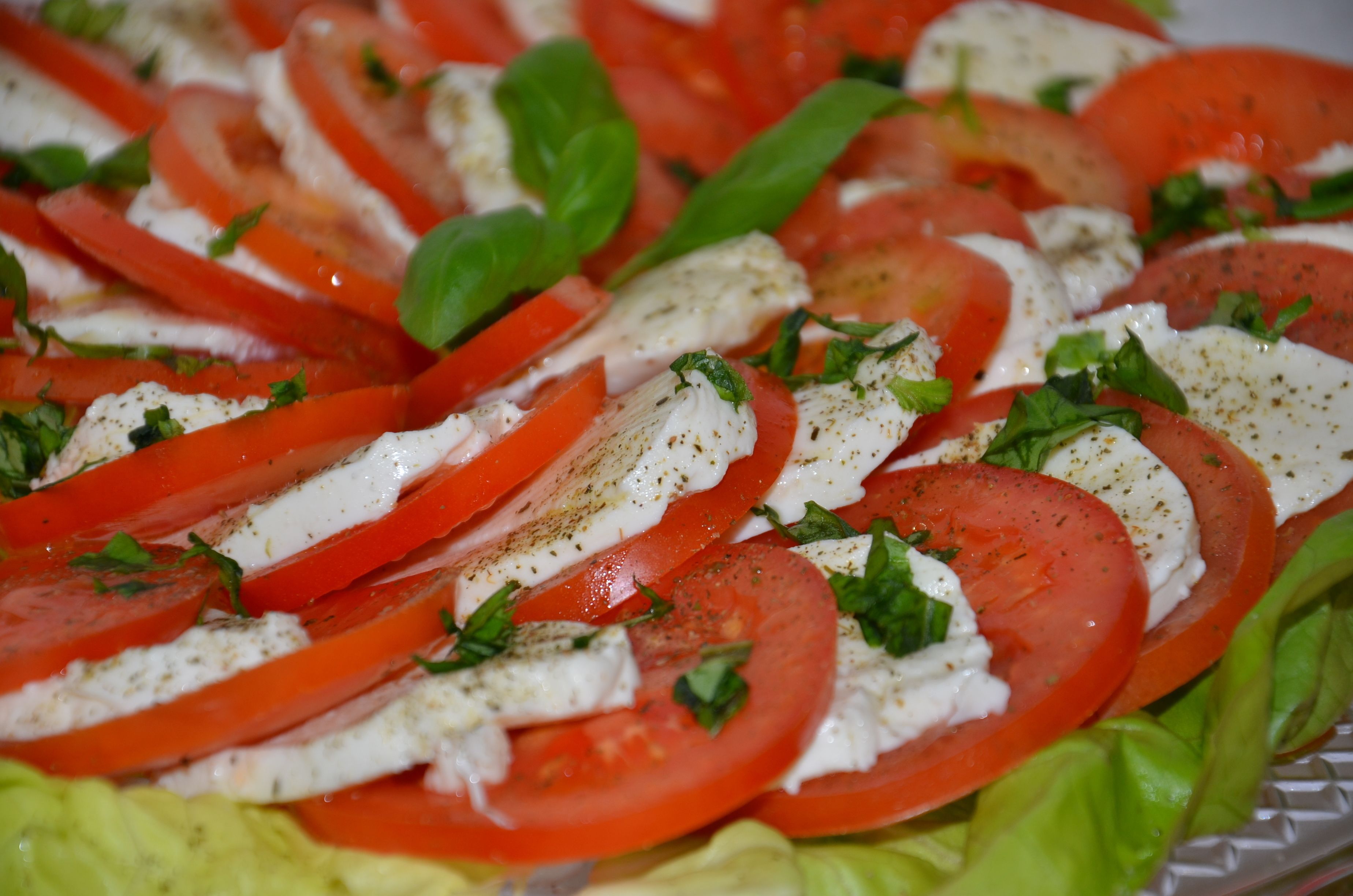 A close-up of a tomato and mozzarella salad with basil leaves.