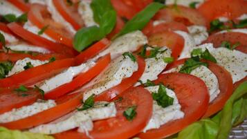 A close-up of a tomato and mozzarella salad with basil leaves.