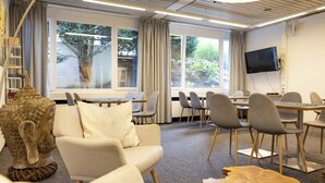 A modern conference room with a sofa, chairs, a table, and a television. - Hotel Vetter (Nuertingen)