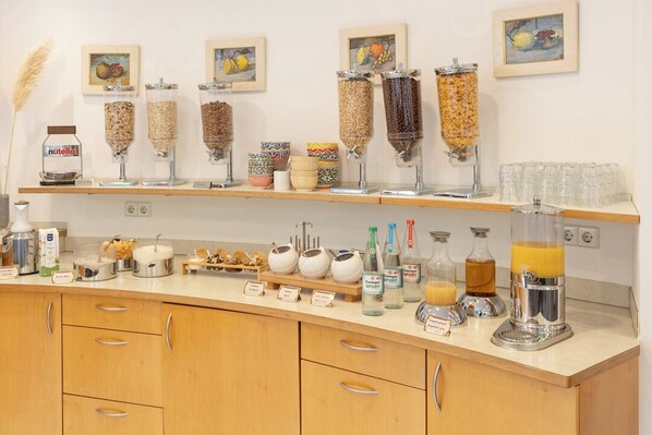 A breakfast bar with various food dispensers, a coffee machine, and a juice dispenser. - Hotel Vetter (Nuertingen)