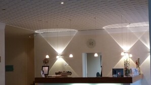 A reception desk with a lighted front panel, a clock, and pendant lighting. - DAHL Hotel & Restaurant GmbH (Wachtberg)