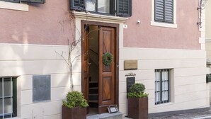 Un bâtiment avec une porte en bois, une enseigne au-dessus de la porte et deux jardinières au sol.