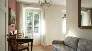 Une pièce comprenant une table à manger, des chaises, un canapé, un lustre et un grand miroir.