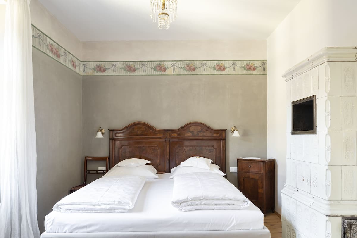 A bedroom with a large bed, two bedside tables, a wooden headboard, and a chandelier.