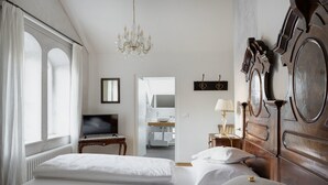 Une chambre d’hôtel avec deux lits, une télévision, un lustre et une salle de bain visible à travers une porte ouverte.